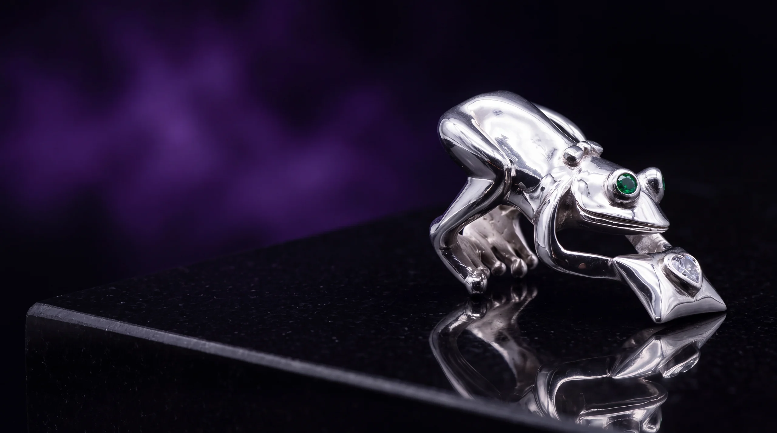 Le Crapaud, bague métal blanc poli miroir, pièce unique MILLE 618 N° 001, posée sur une dalle d'obsidienne